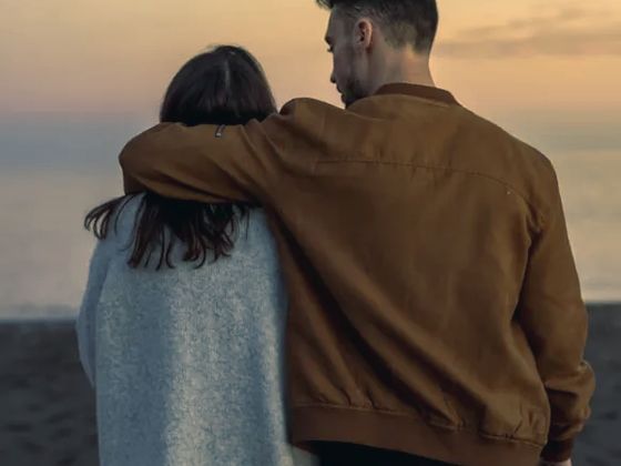 A couple walking together on a beach at sunset